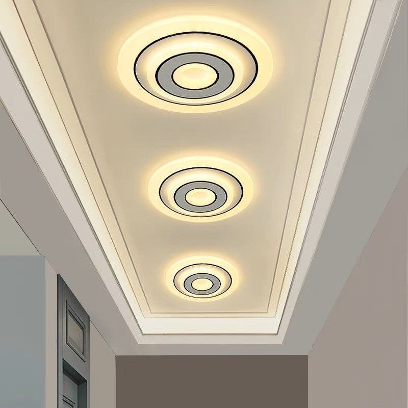 Plafoniera LED cu inele concentrice aprinsa in lumina calda, montata pe tavan coridor modern