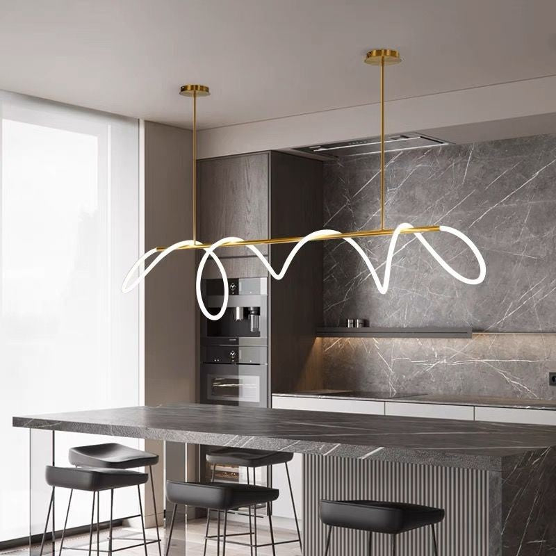 Lustra LED cu tub luminos ondulat auriu montata deasupra insulei de bucatarie moderna