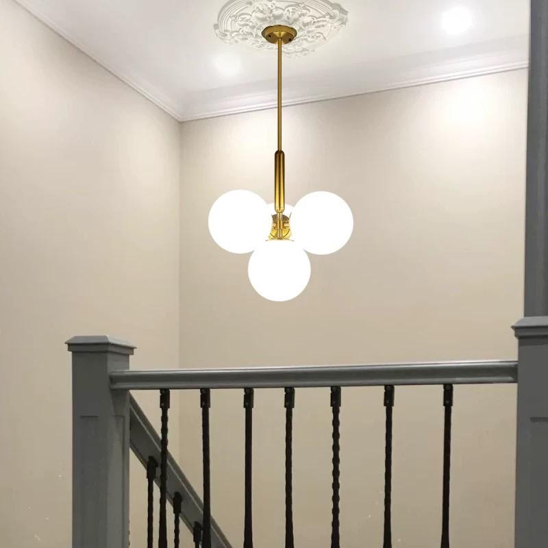 Lustra cu globuri opaline auriu mat instalata deasupra casei scarii, perspectiva de jos in sus