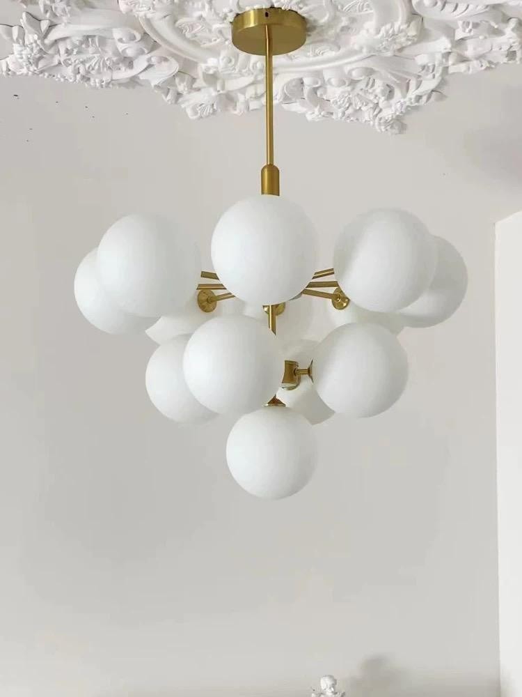 Candelabru cu 13 globuri albe grupate compact, structura aurie, detaliu rozeta decorativa tavan