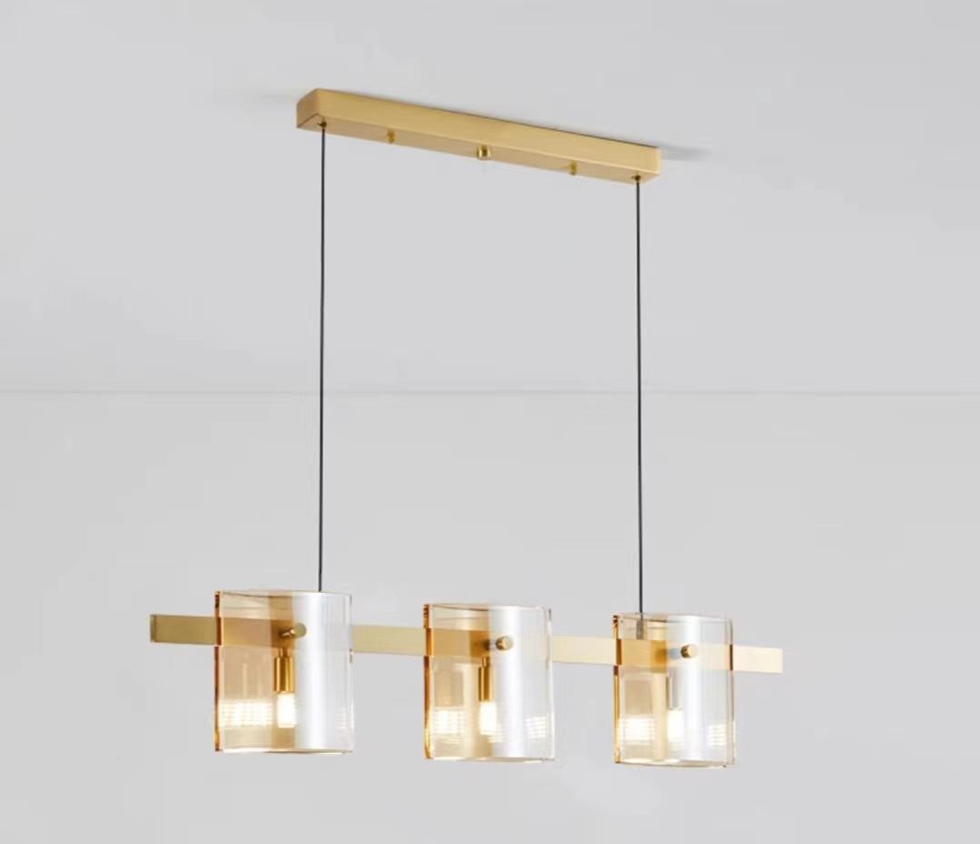Lustra suspendata cu 3 abajururi cilindrice din sticla, structura metalica aurie, soclu G9, lungime 800 mm