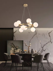 Lustra cu globuri albe si structura aurie montata deasupra mesei de dining intr-un interior modern