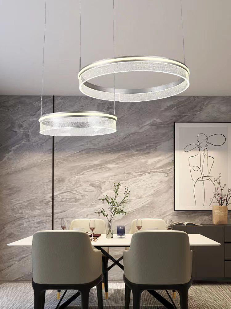 Lustra LED cu inele suspendate deasupra mesei de sufragerie, atmosfera moderna, lumina calda si neutra reglabila