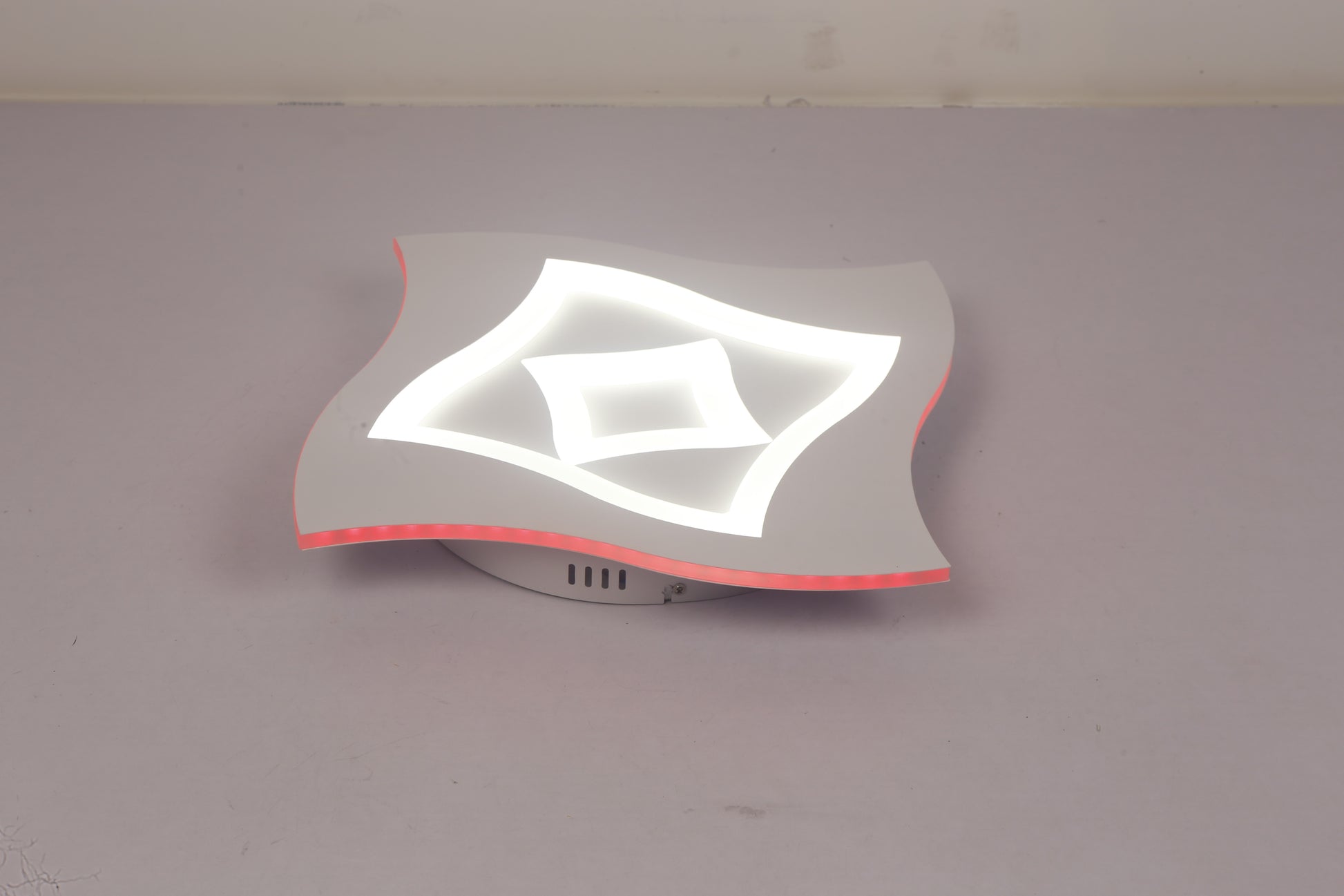 Plafoniera LED aprinsa cu lumina alba rece si contur RGB rosu, vedere laterala pe fond neutru