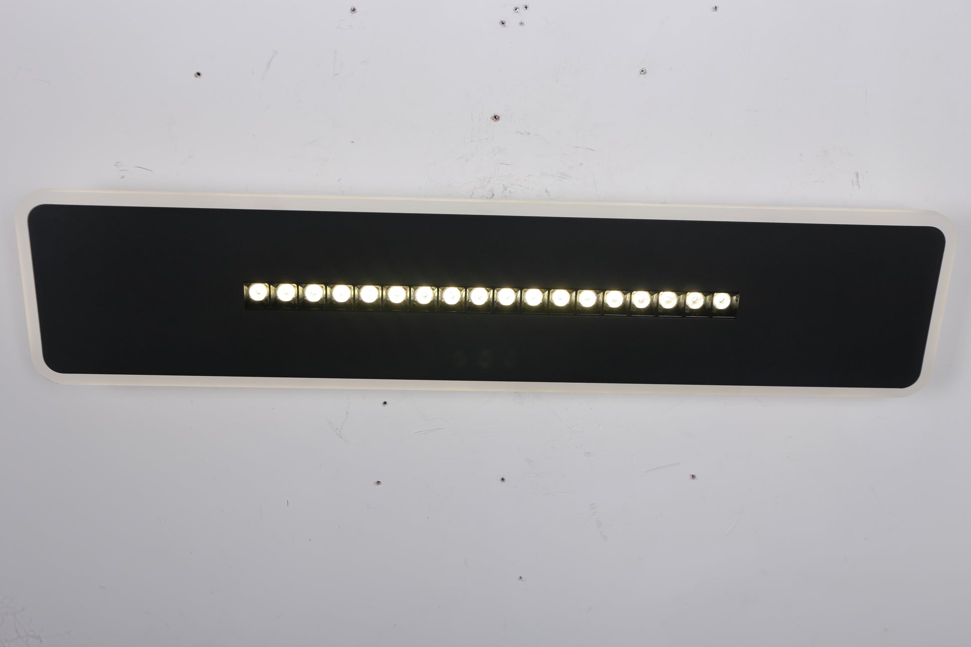 Corp LED dreptunghi negru montat pe perete, spoturile centrale aprinse, lumina neutra uniforma
