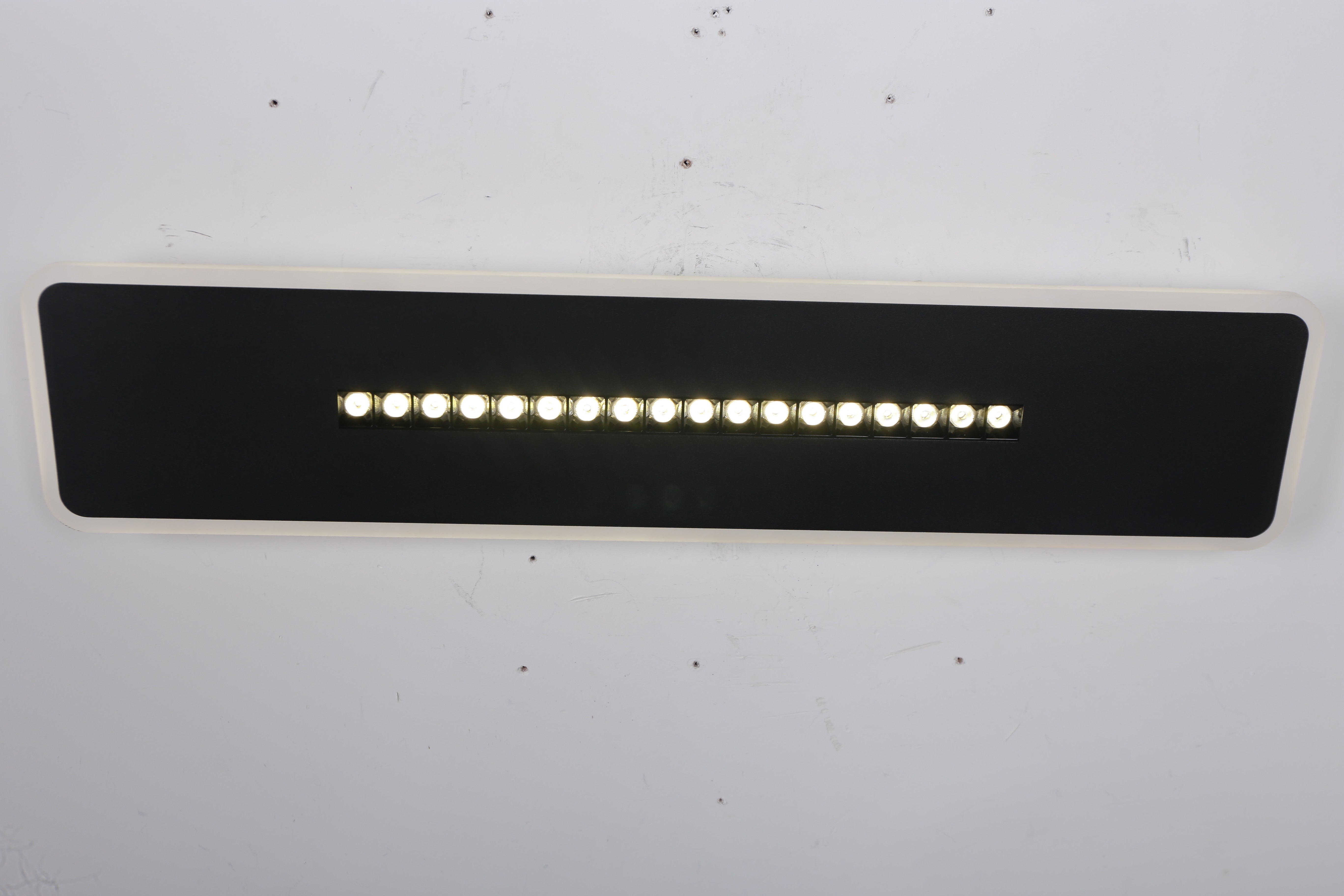 Corp LED dreptunghi negru montat pe perete, spoturile centrale aprinse, lumina neutra uniforma