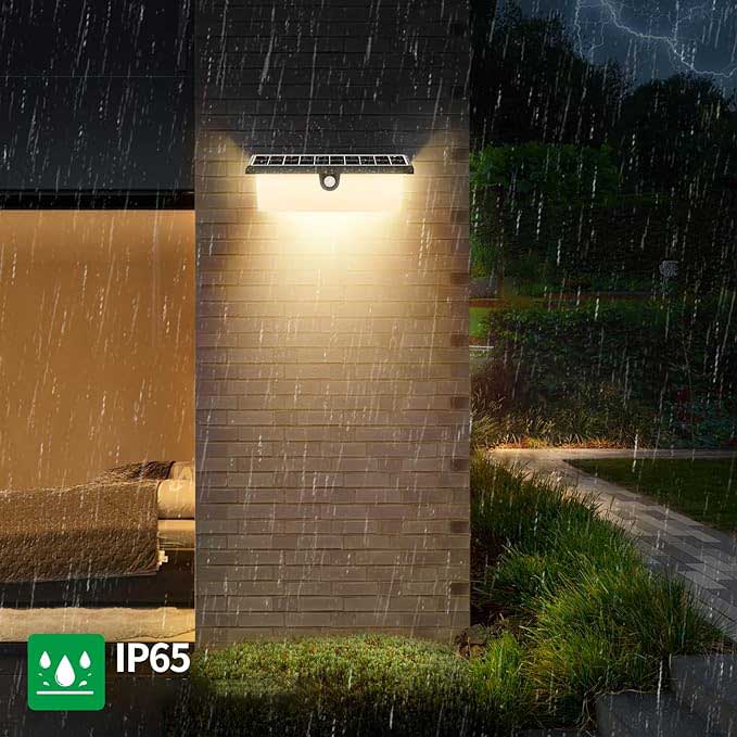 Lampa solara de perete IP65 in functiune pe timp de ploaie, lumina calda pe fatada exterioara