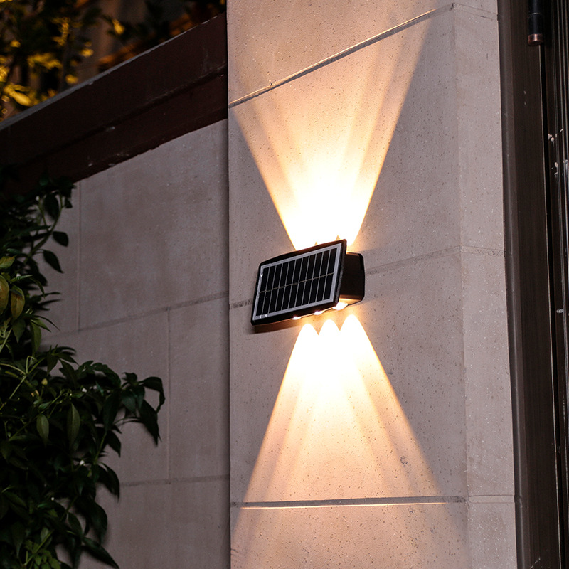 Aplica solara de perete exterior cu fascicule sus-jos pe zid de piatra, lumina calda decorativa
