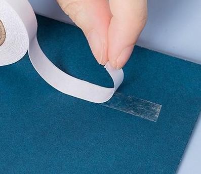 banda dublu adeziva de hartie trasa de pe rola si aplicata pe material textil albastru