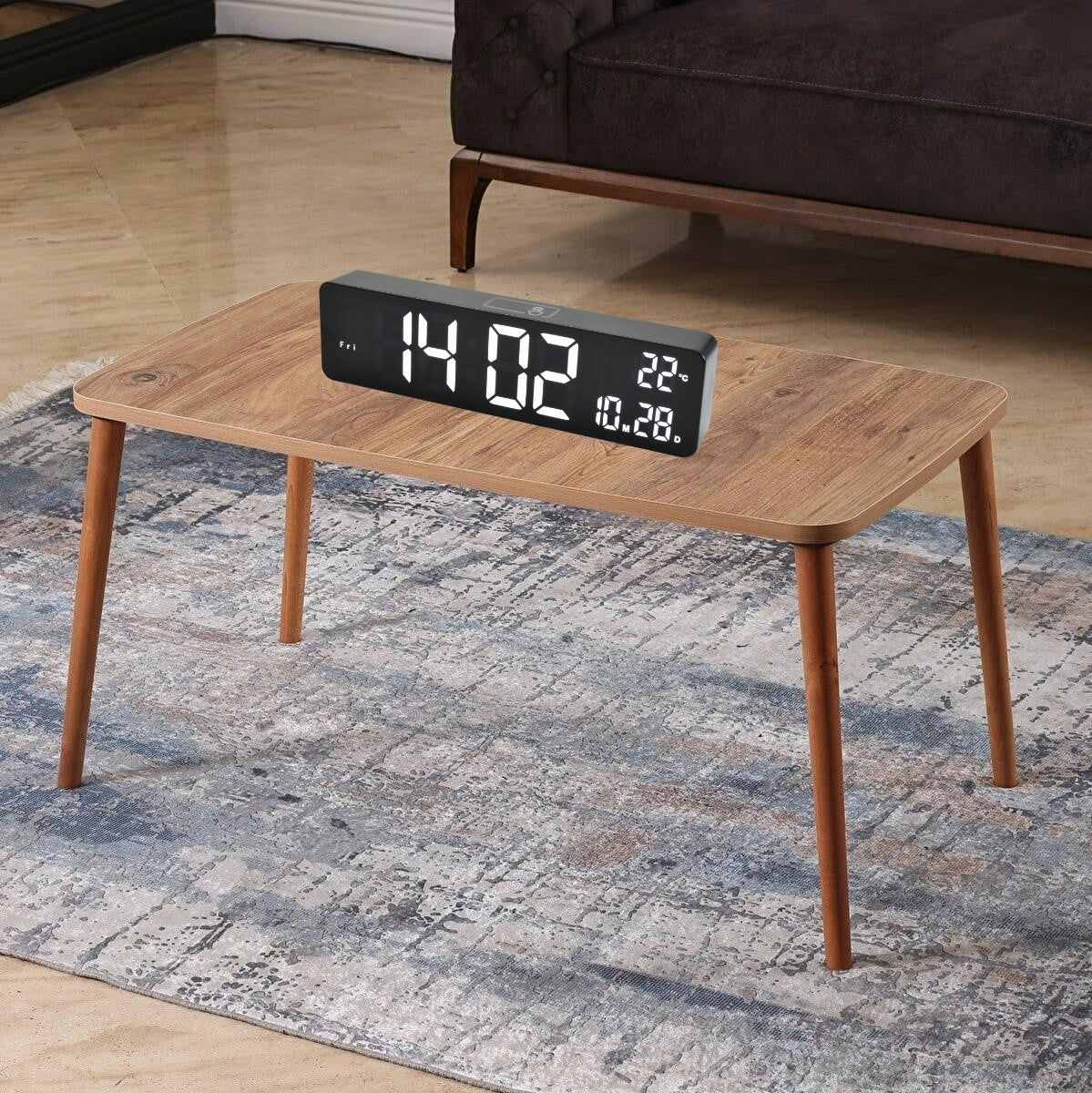 Ceas digital LED negru asezat pe masuta din living, afisaj ora si temperatura vizibil de la distanta